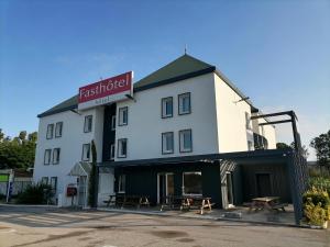 - un grand bâtiment blanc avec un panneau dans l'établissement FastHotel Montpellier Ouest - Un Hôtel FH Classic, à Saint-Jean-de-Védas