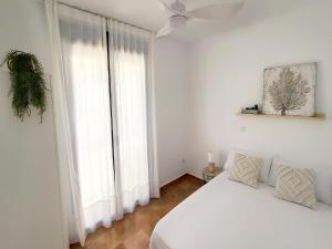 a bedroom with a white bed and a large window at El Escondite de Gredos in Lanzahita