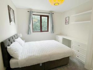 a white bedroom with a bed and a window at Oxford City Centre House With Parking in Oxford