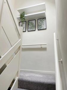 a white staircase with two pictures on the wall at Oxford City Centre House With Parking in Oxford