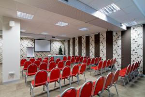 a conference room with red chairs and a screen at Hotel Cosmopolitan Bologna in Bologna