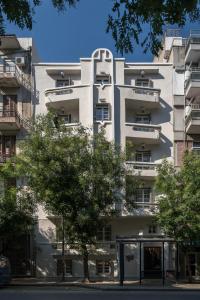 un edificio bianco con un albero di fronte di 72 AD Suites a Salonicco