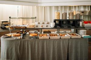 una linea a buffet con prodotti da forno e altri prodotti alimentari di Hotel Cosmopolitan Bologna a Bologna