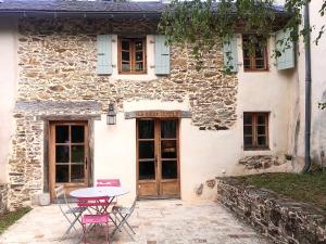 una mesa y sillas frente a una casa de piedra en La Ferme bio de la Salvanié en Bellegarde