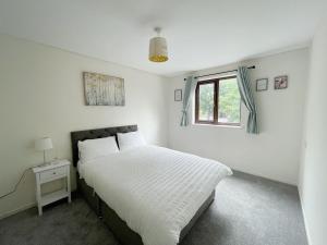 a white bedroom with a bed and a window at Oxford City Centre House With Parking in Oxford