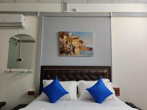 ein Bett mit blauen Kissen und ein Bild darüber in der Unterkunft Regina's Place in Mandrem