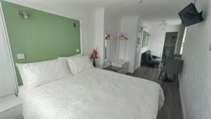 a bedroom with a white bed with a green wall at Orient B&B in Holyhead