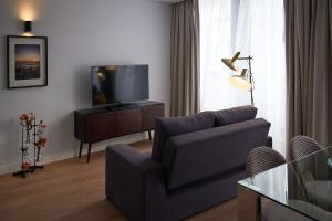 a living room with a couch and a flat screen tv at Hotel Cruzeiro in Angra do Heroísmo