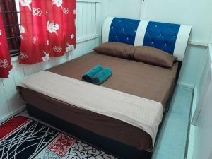 a small bed in a room with a blue headboard at AMZ WOODHOMESTAY AT GONG KIAT, KUALA TERENGGANU in Kuala Terengganu