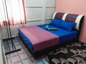 a bedroom with a bed with blue and purple at AMZ WOODHOMESTAY AT GONG KIAT, KUALA TERENGGANU in Kuala Terengganu +12 photos
