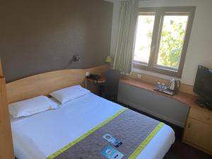 ein Hotelzimmer mit einem Bett und einem Fenster in der Unterkunft Kyriad Montpellier Aéroport - Gare Sud de France in Mauguio