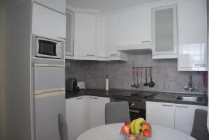 una cocina con armarios blancos y un bol de fruta en una mesa en Apartamento A Cascada, en Cee
