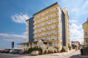 a tall yellow building with cars parked in a parking lot at Howard Johnson Plaza by Wyndham Ocean City Oceanfront in Ocean City