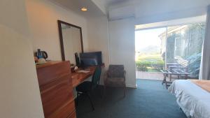 a hotel room with a desk and a bed and a window at Mountain View International by BON Hotels in Mbabane