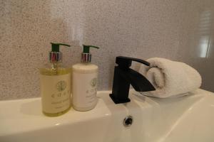 a bathroom sink with two bottles of soap and a towel at The Gwydir Ground Floor Studio in Llandudno