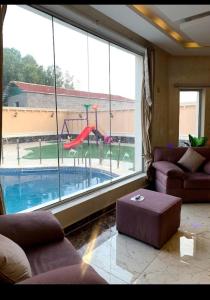 a living room with a view of a swimming pool through a large window at منتجع زهرة سلسبيل بالمدينه المنورة in Medina