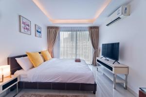 um quarto com uma cama, uma secretária e uma televisão em AMAZING VIEW Studio in Laguna Beach Resort 2. em Praia de Jomtien