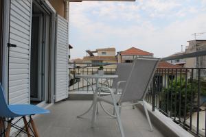 een patio met een tafel en stoelen op een balkon bij Urban Chic Apartments Lefkada in Lefkada