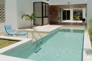 a swimming pool with a chair and a house at Villa Casa Agua in Akumal