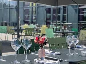 a table with wine glasses and a vase of flowers at Aiden by Best Western Clermont-Ferrand - Le Magnetic Hotel & Spa in Clermont-Ferrand
