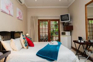 a bedroom with a bed with a blue blanket on it at Riverbank Lodge in Upington
