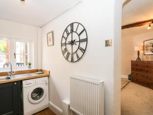 a kitchen with a washing machine and a clock on the wall at Cuckoo Cottage in Worcester +38 photos