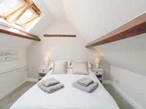 a bedroom with a white bed with two pillows on it at Cuckoo Cottage in Worcester