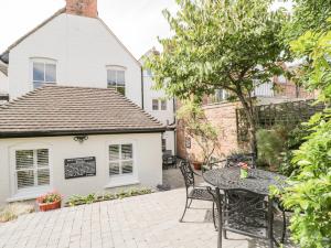a patio with a table and chairs in front of a house at Cuckoo Cottage in Worcester