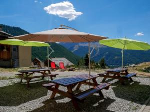 due tavoli da picnic con ombrelloni in cima a una montagna di Chalet le Genepy with amazing views! a Molines-en-Queyras