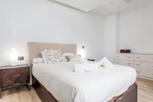 1 dormitorio blanco con 2 camas y mesita de noche en CASA ESPECTACULAR DE DISEÑO CON JARDIN INTERIOR en Valencia