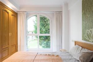 una camera da letto con una grande finestra e un letto di NEW Apartment & Terrace. Steps to Ondarreta Beach a Añorga-Lugariz