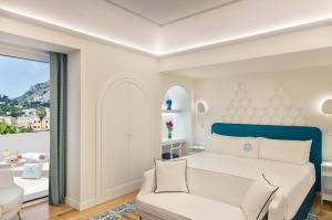 a bedroom with a white bed and a couch at Pazziella Garden & Suites in Capri