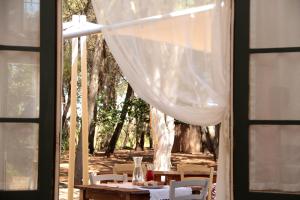 einen Tisch mit Stühlen und einem weißen Vorhang in der Unterkunft Masseria Cristo in Ugento