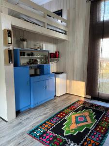a kitchen with blue cabinets and a rug on the floor at Soko House in Sokolac +16 photos