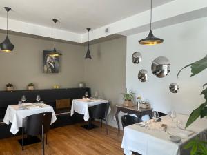 un restaurant avec deux tables, des chaises et des lampes suspendues dans l'établissement Hôtel - Spa Les Corderies, à Saint-Valery-sur-Somme