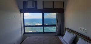 een slaapkamer met uitzicht op de oceaan vanuit een raam bij Marazú OndinaApart in Salvador