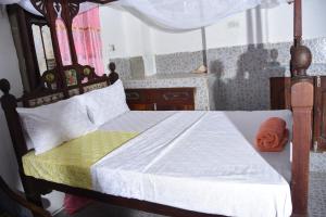 ein Schlafzimmer mit einem Bett mit einem Bettrahmen aus Holz in der Unterkunft BABAbora house in Ngambo