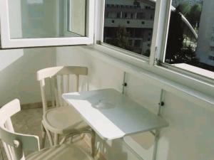una mesa blanca y sillas frente a una ventana en Апартамент Арена Бургас 5+1 човека, en Burgas