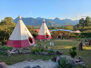 two tents in a yard with a house at BIOSFERA LODGE GLAMPING tipi 2 personas in Oxapampa