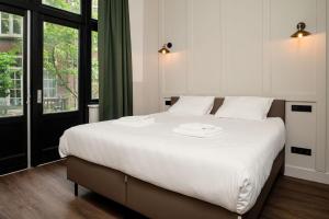 Un dormitorio con una gran cama blanca y una ventana en Mr.Lewis Rotterdam, en Róterdam