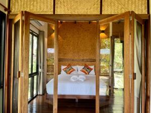 een slaapkamer met een bed in een kamer met glazen deuren bij Kunna House in Ko Yao Noi