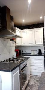 a kitchen with white cabinets and a stove top oven at Victoria's Apartment - 3 Large Bedroom in Blackpool