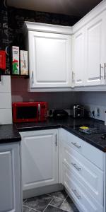 eine Küche mit weißen Schränken und einer roten Mikrowelle in der Unterkunft Victoria's Apartment - 3 Large Bedroom in Blackpool