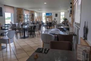 um restaurante com mesas e cadeiras num quarto em Logis Hôtel Volcan Sancy em Nébouzat