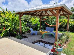 a wooden gazebo with two chairs and a table at Villa Ohana in Sainte-Anne