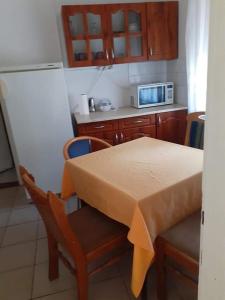 eine Küche mit einem Tisch, Stühlen und einer Mikrowelle in der Unterkunft Malomtavi Vendégház Tapolca in Tapolca