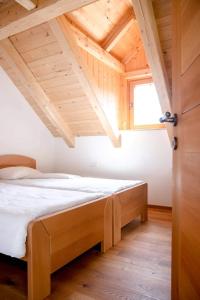een bed in een kamer met een houten plafond bij Apartma Mlekuž in Bovec