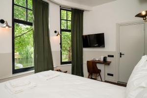 a bedroom with a bed and a desk and windows at Mr.Lewis Rotterdam in Rotterdam