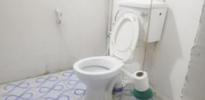 - des toilettes blanches dans une salle de bains avec un rouleau de papier toilette dans l'établissement BABAbora house, à Ngambo