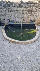 un estanque con una fuente frente a una pared de piedra en LE ROCAGERMANOIS - Jolie maison de village, en Saint-Germain-le-Rocheux